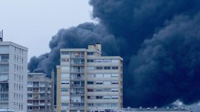 Derrière des immeubles, la fumée noire qui s'échappe de l'usine Luzibrol à Rouen, le 26 septembre 2019. (THIBAUT DROUET / AFP)